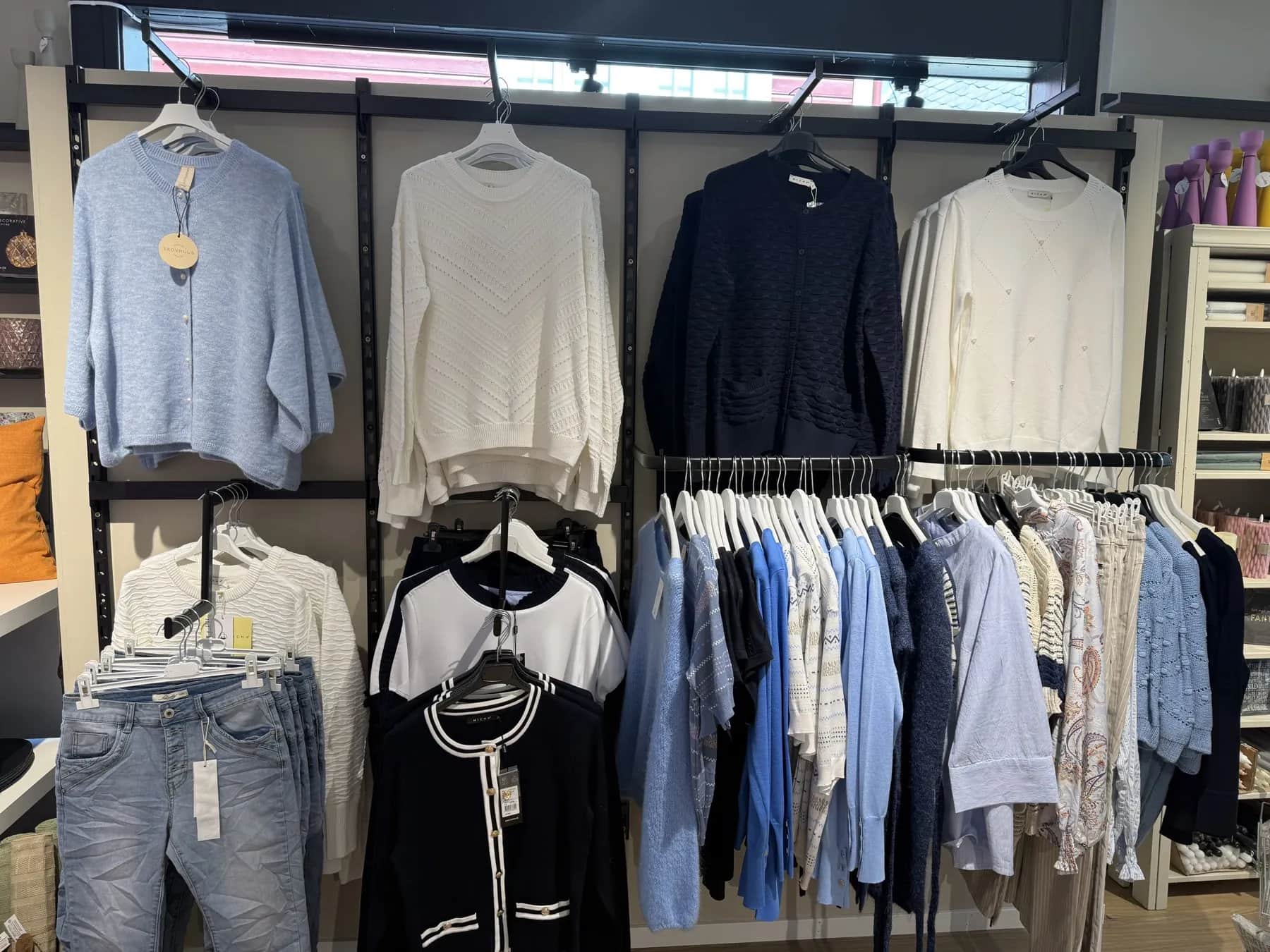 Vegg med strikkegensere i lyseblått, hvitt og marine hos Toves